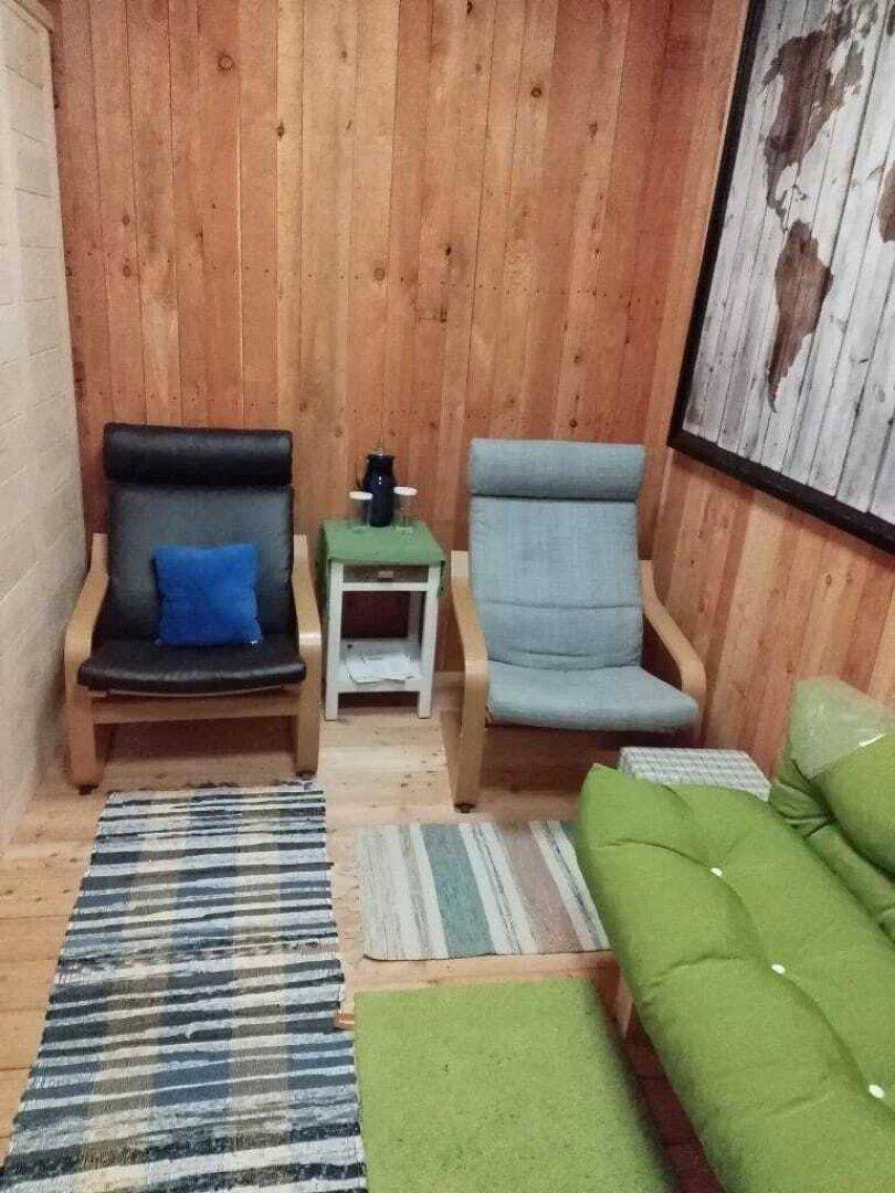 Gemütlicher Entspannungsbereich mit Sesseln, Couch und Holzvertäfelung.