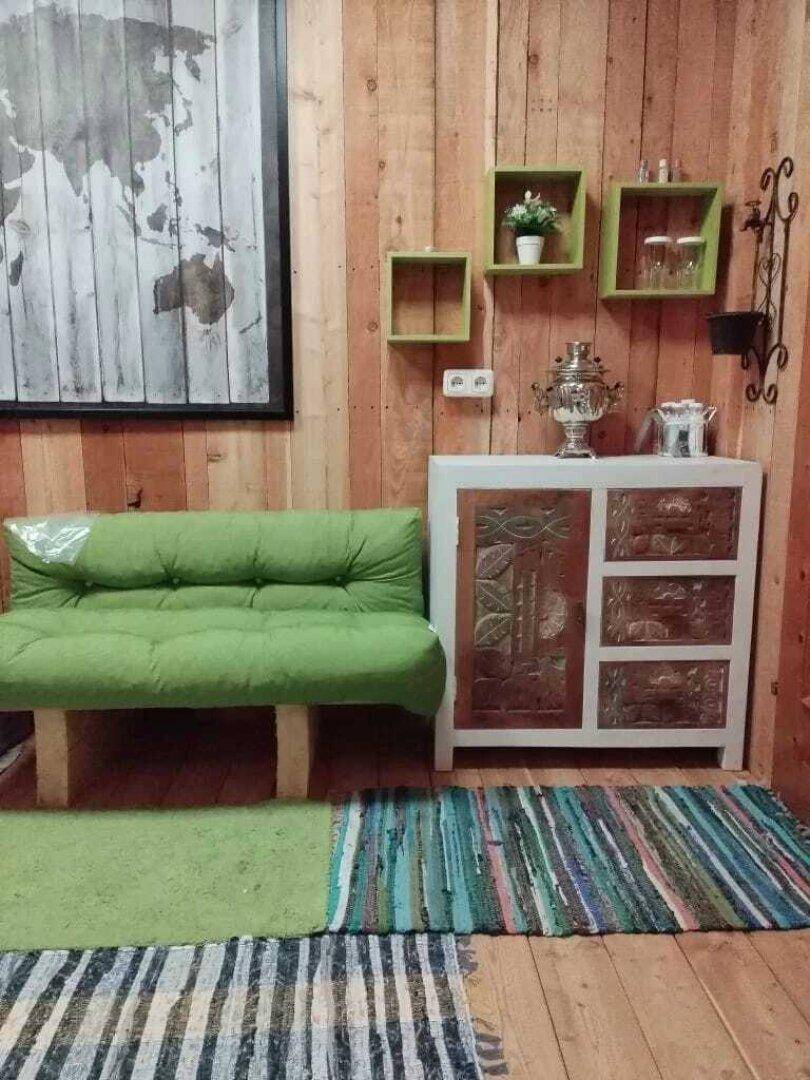 Entspannungsbereich mit grüner Couch, Holzvertäfelung und Weltkarten-Wanddekoration.