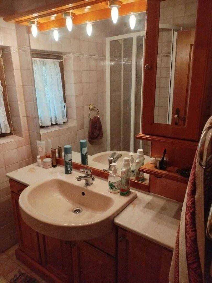 Badezimmer mit rosa Fliesen, Einzelwaschbecken, Spiegelschrank und Duschkabine.