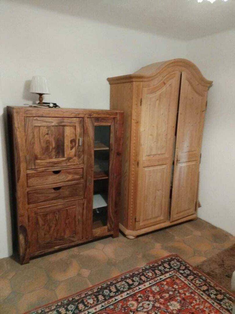 Zwei traditionelle Holzschränke auf einem gefliesten Boden in einem Innenraum.