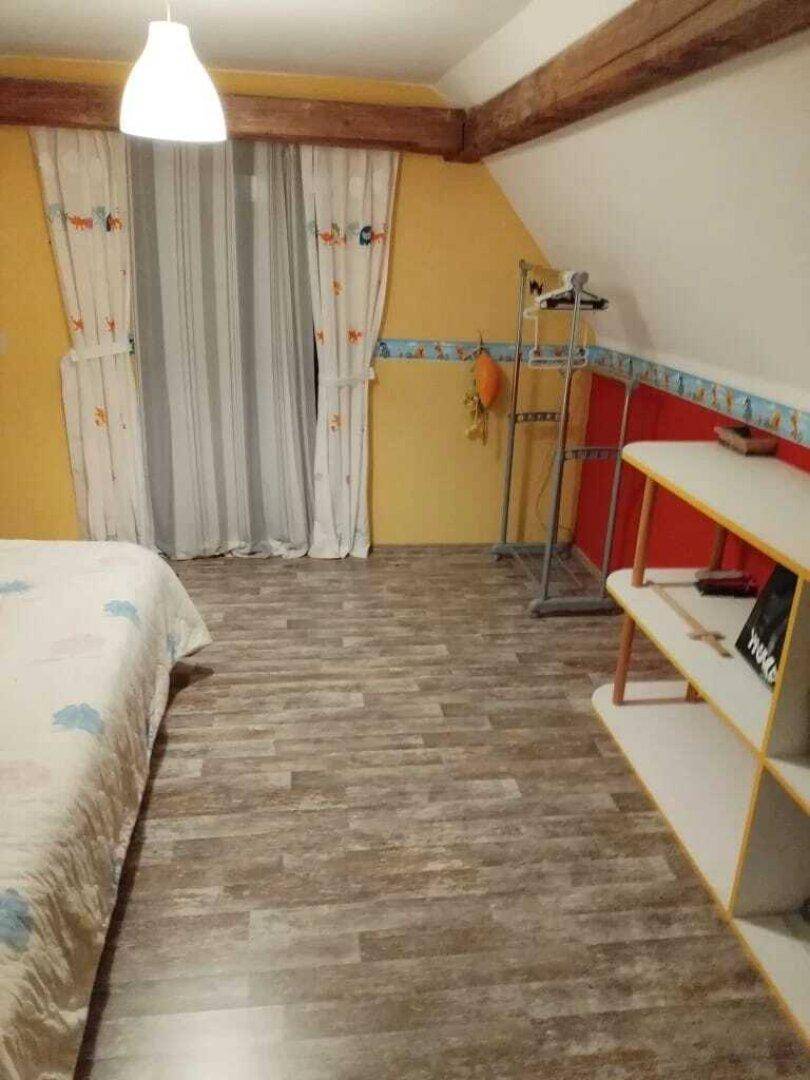 Schlafzimmer im Dachgeschoss mit Holzbalken, Laminatboden und farbenfroher Dekoration.