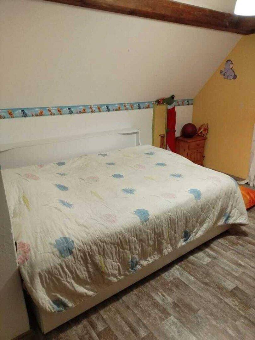 Helles Schlafzimmer im Dachgeschoss mit Doppelbett und Laminatboden.