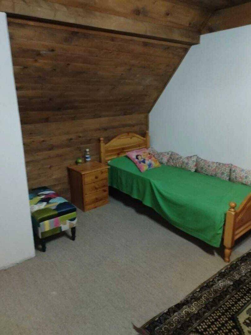 Kleines Schlafzimmer im Dachgeschoss mit Einzelbett, Holzvertäfelung und Teppichboden.