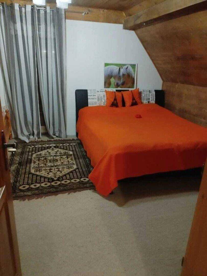 Schlafzimmer im Dachgeschoss mit Doppelbett, Teppichboden und Holzvertäfelung.