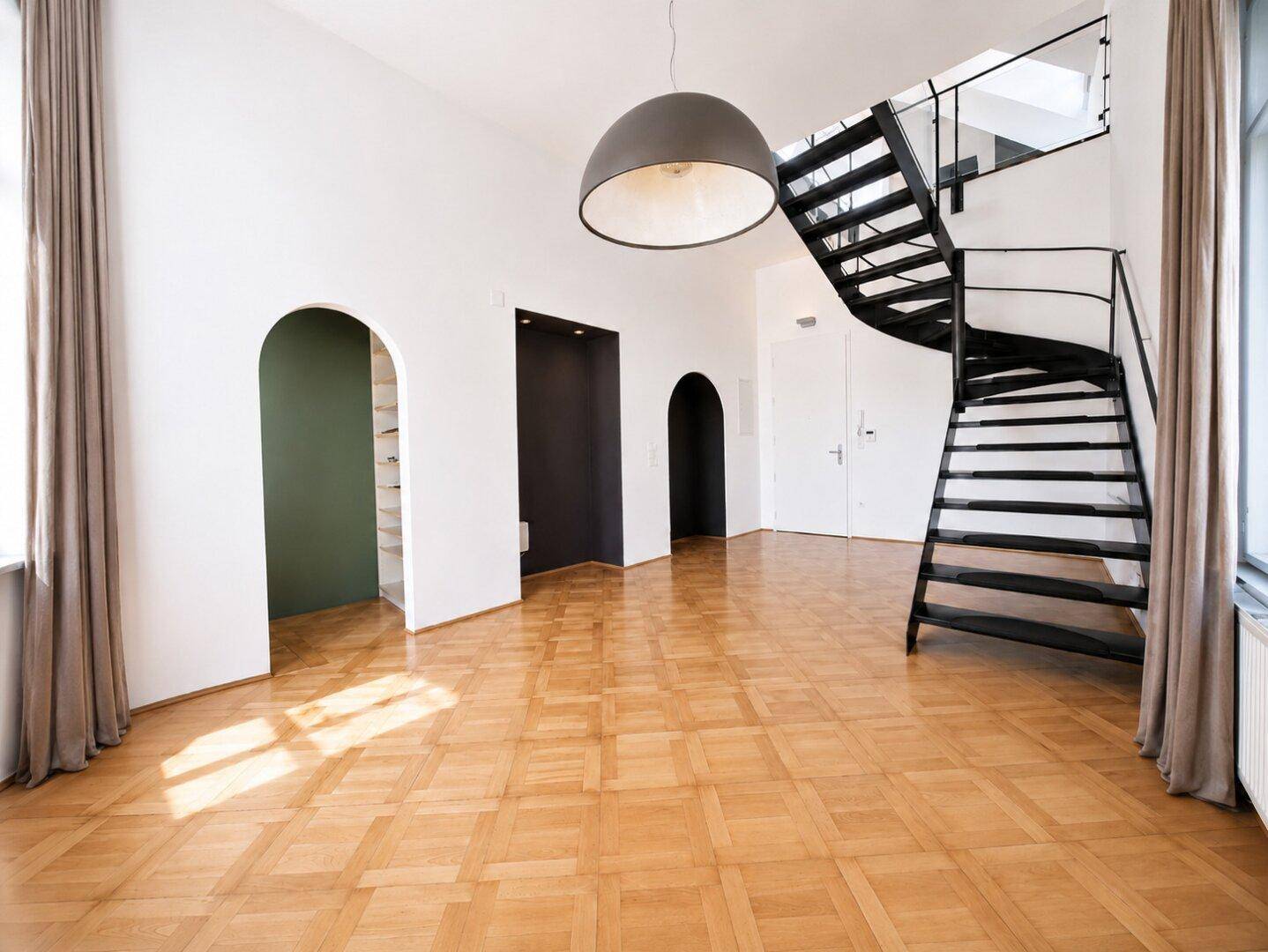 Geräumiges Wohnzimmer mit Fischgrätparkett, moderner Wendeltreppe und hohen Decken.