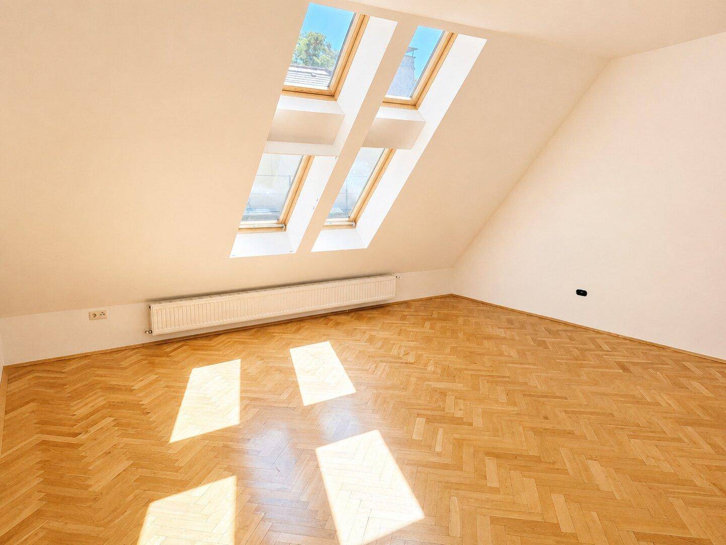 Helles Schlafzimmer mit Fischgrätparkett und mehreren Dachfenstern für viel Tageslicht.