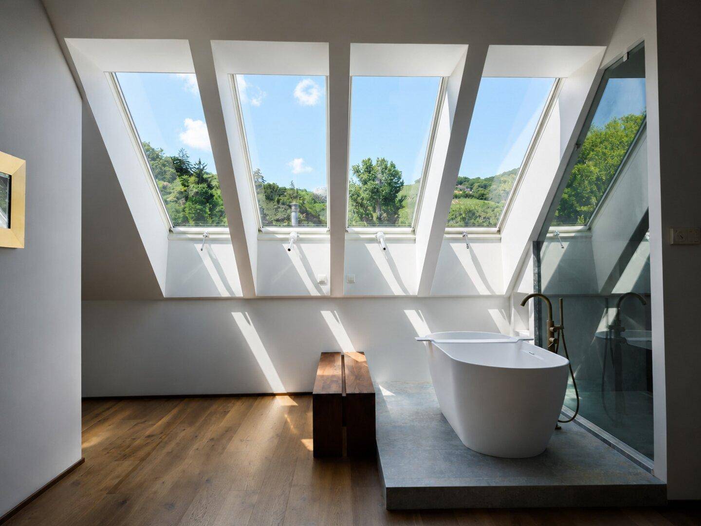 Luxuriöses Badezimmer mit freistehender Badewanne, Holzboden und großen Dachfenstern mit Weitblick.