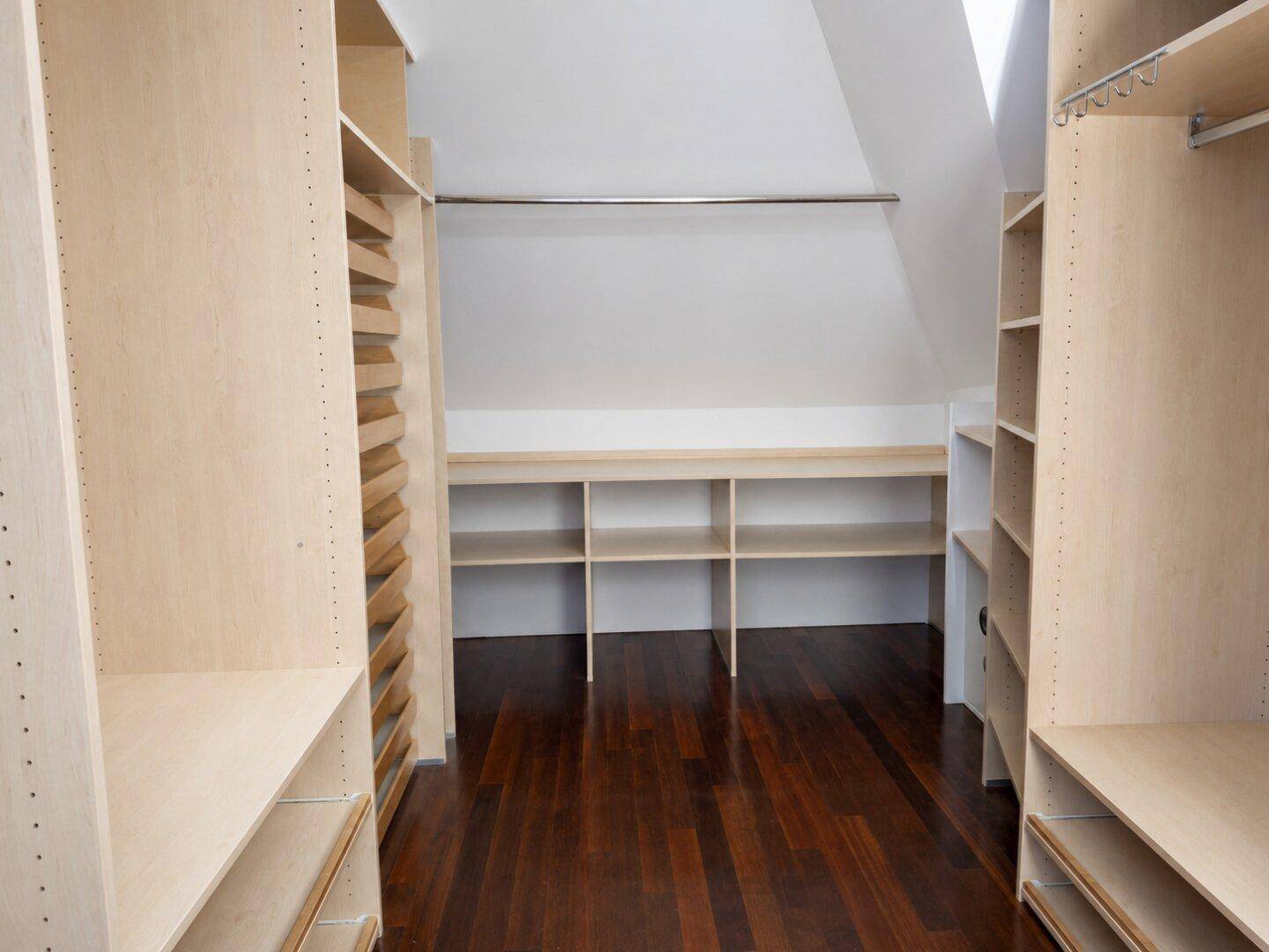 Geräumiger begehbarer Kleiderschrank mit Holzböden und maßgefertigten Regalsystemen.