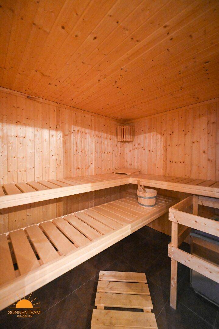 Geräumige Holzsauna mit mehreren Bänken und traditionellem Saunaeimer.