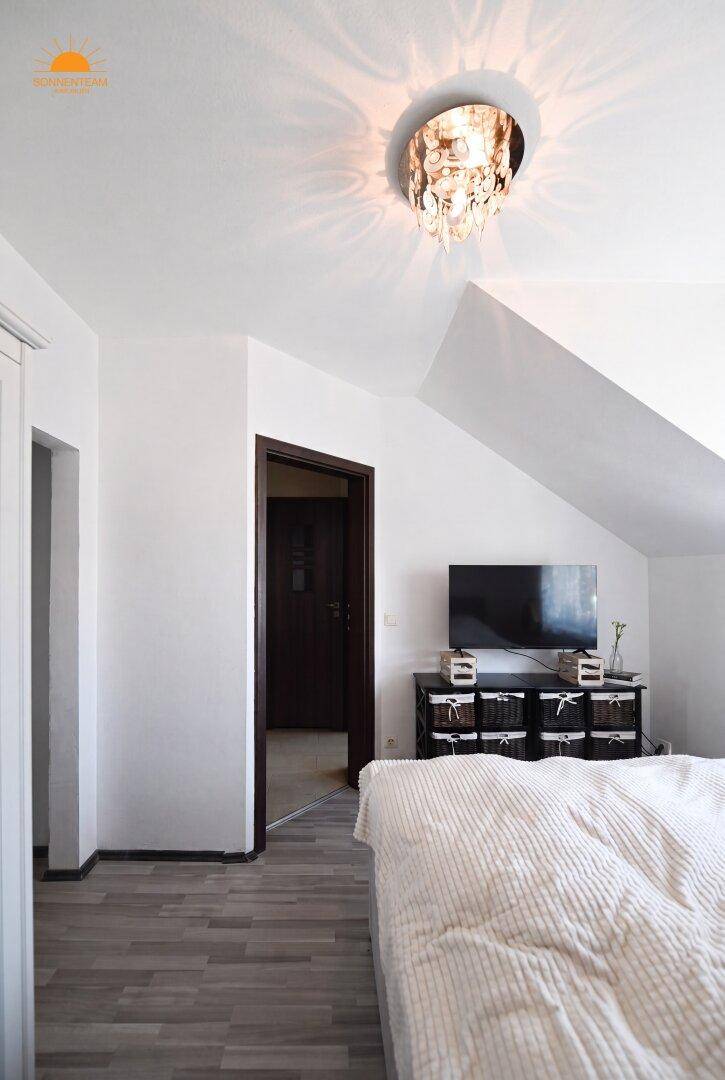 Gemütliches Schlafzimmer im Dachgeschoss mit schrägen Wänden und Holzboden.