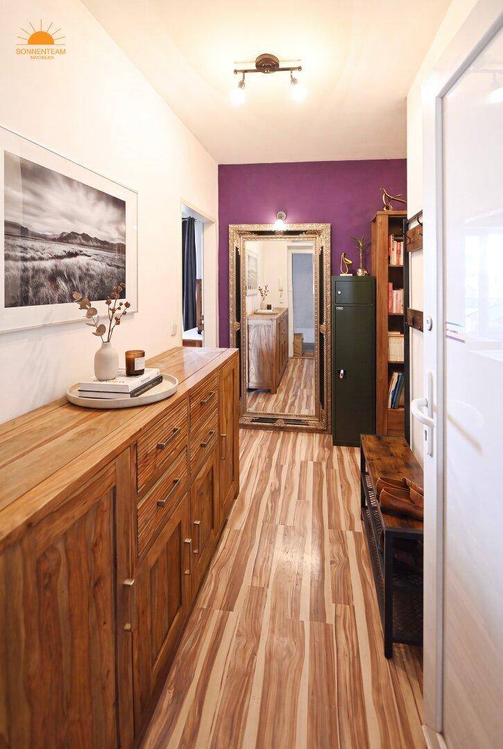 Heller Flur mit Holzboden, großer Kommode und einem dekorativen Spiegel an der Wand.