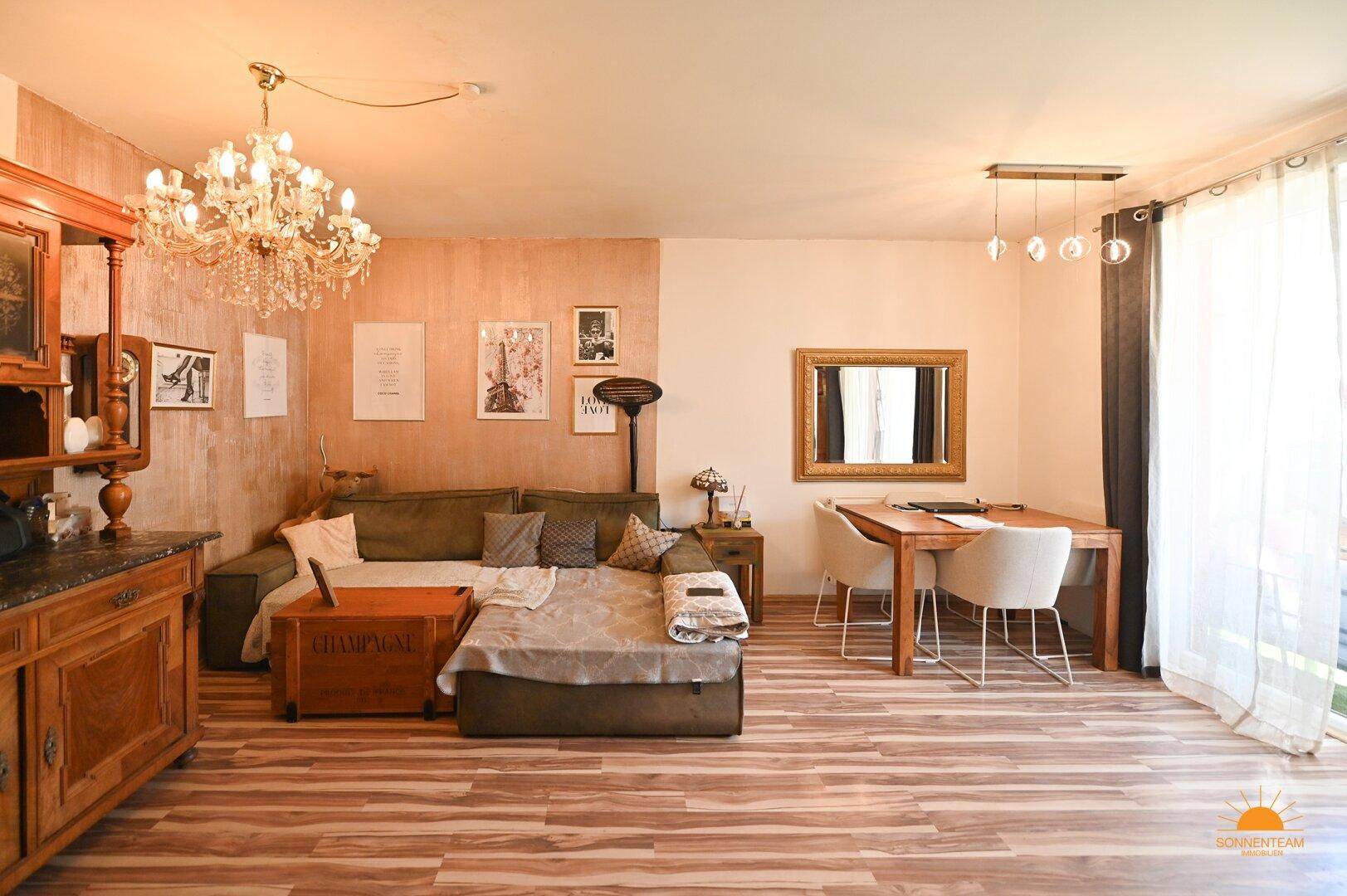 Gemütlicher Wohn-Essbereich mit Holzboden, Kronleuchter und direktem Zugang zur Terrasse.