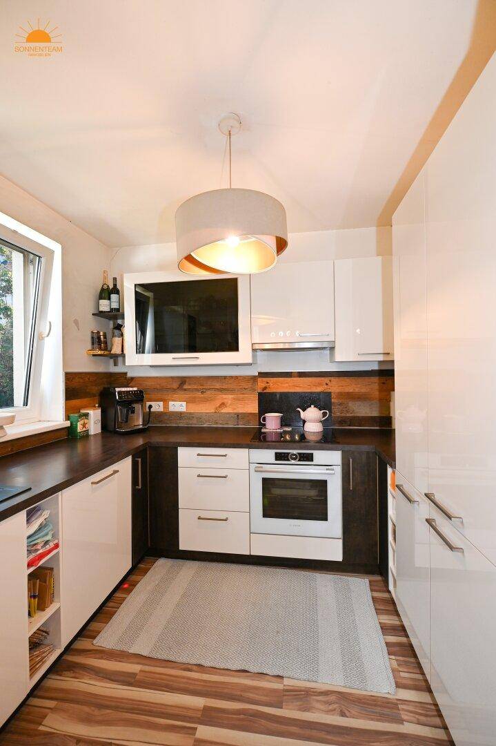 Moderne Küche mit weißen Hochglanzfronten, Holzakzenten und integrierten Geräten.
