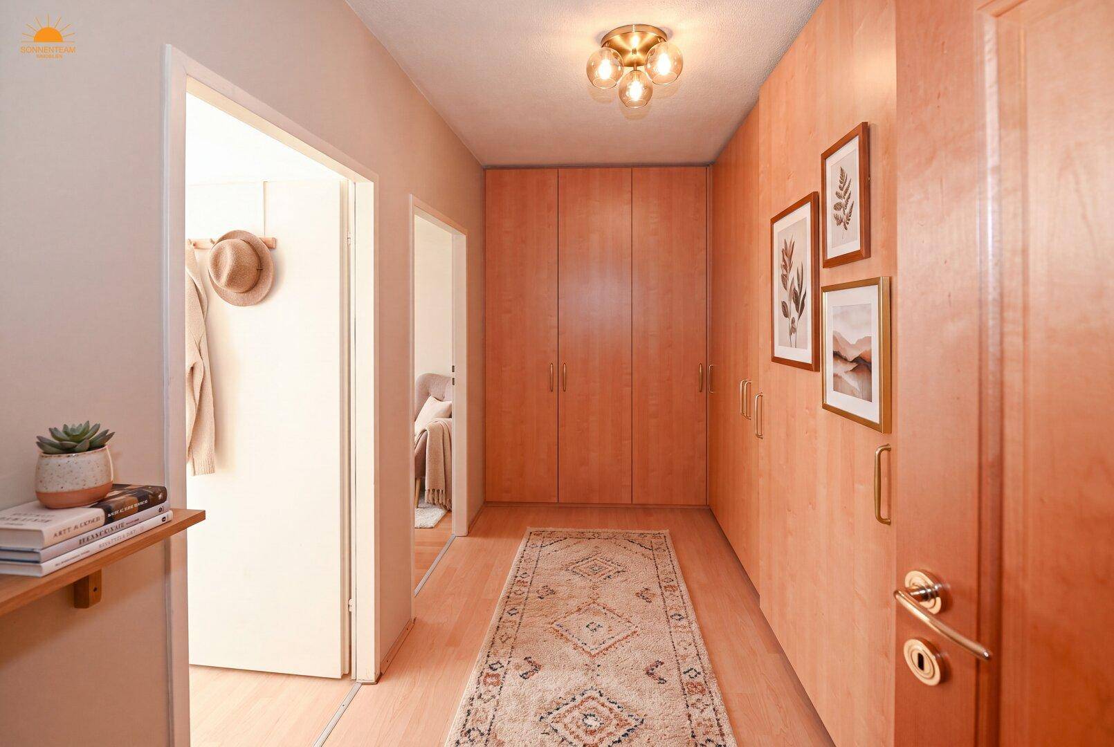 Heller Flur mit Einbauschränken aus Holz und einem dekorativen Teppich.