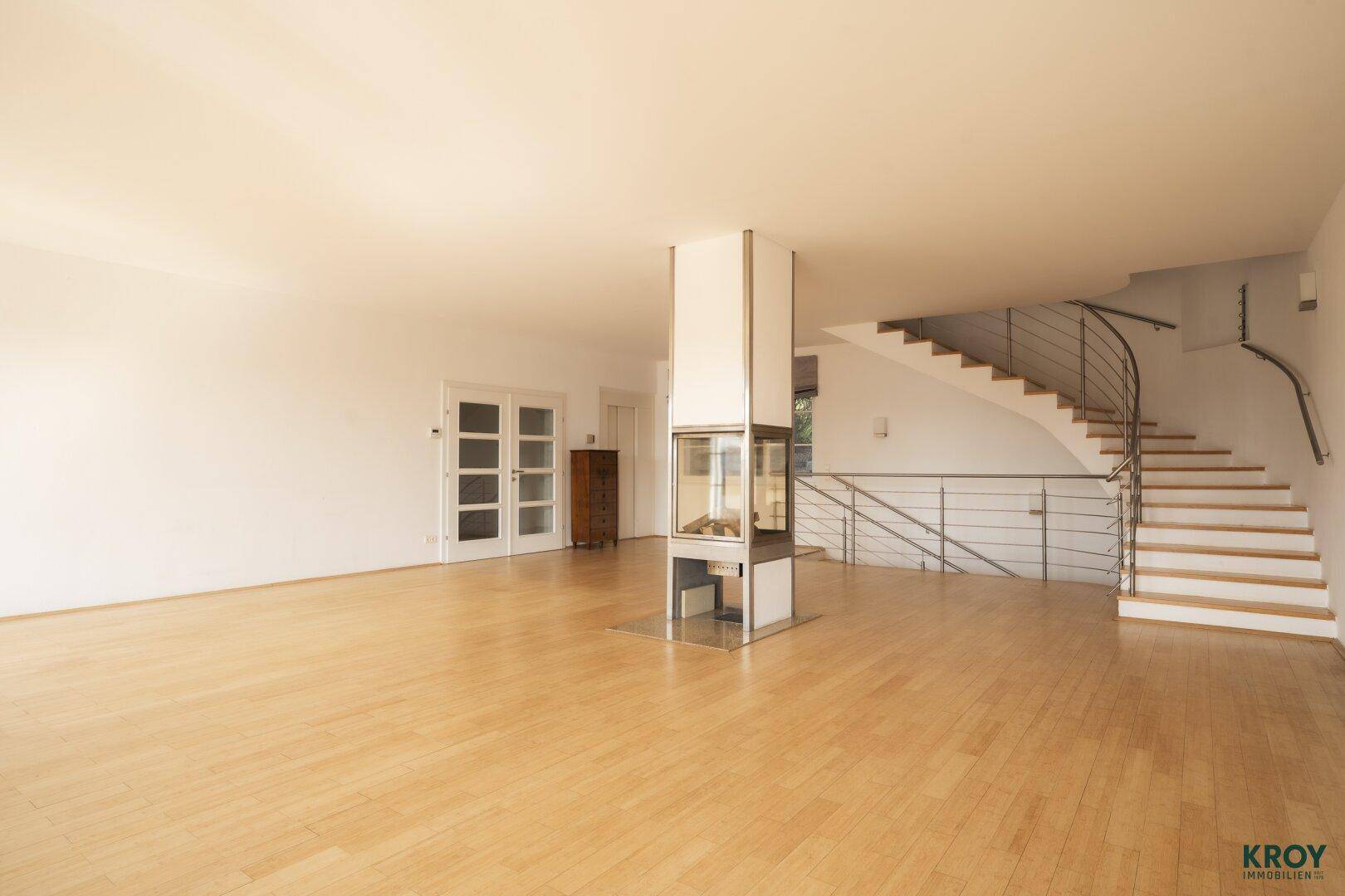 Geräumiges Wohnzimmer mit Holzboden, modernem Kamin und eleganter Wendeltreppe.