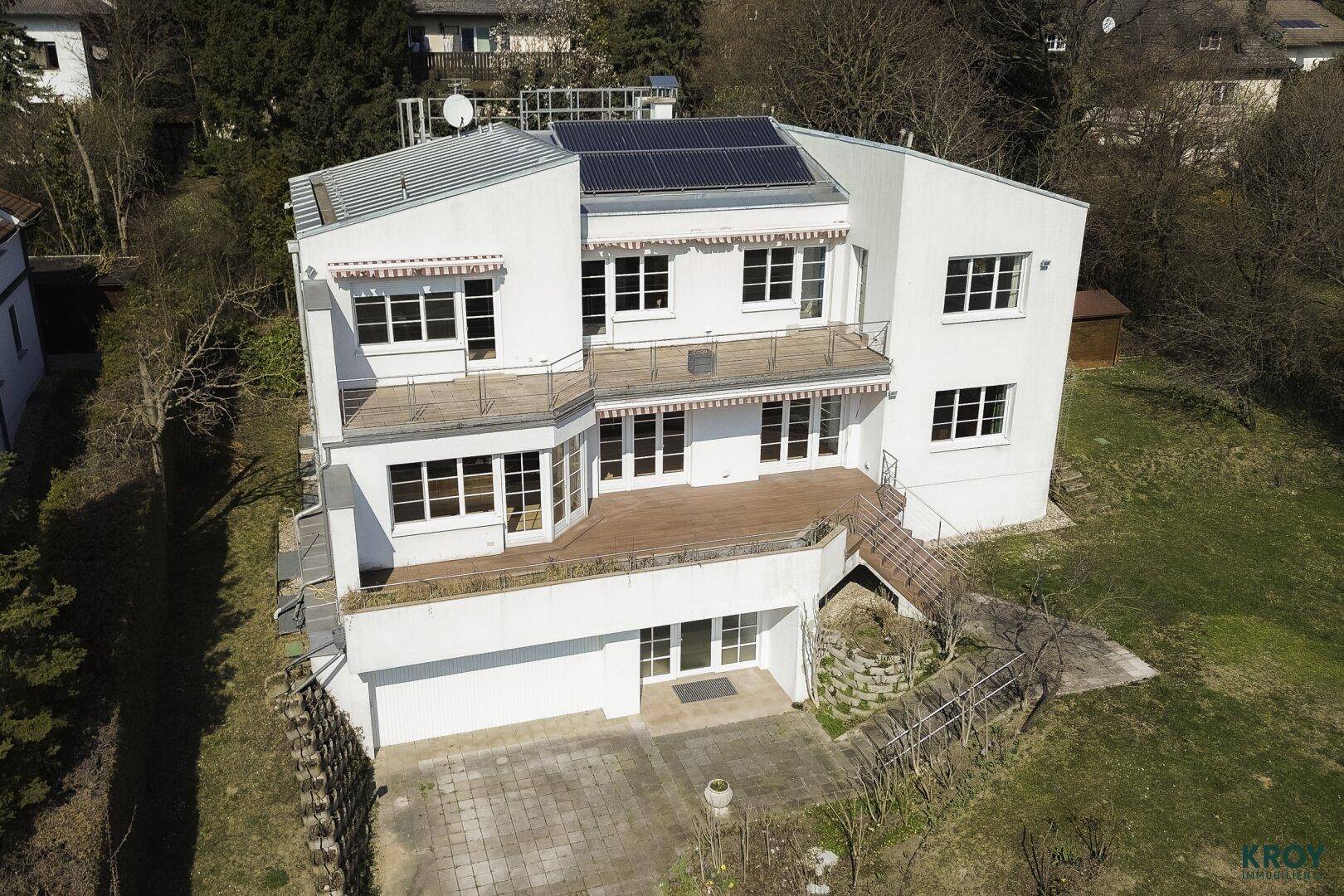 Luftaufnahme des modernen weißen Gebäudes mit mehreren Balkonen und Solarpaneelen auf dem Dach.