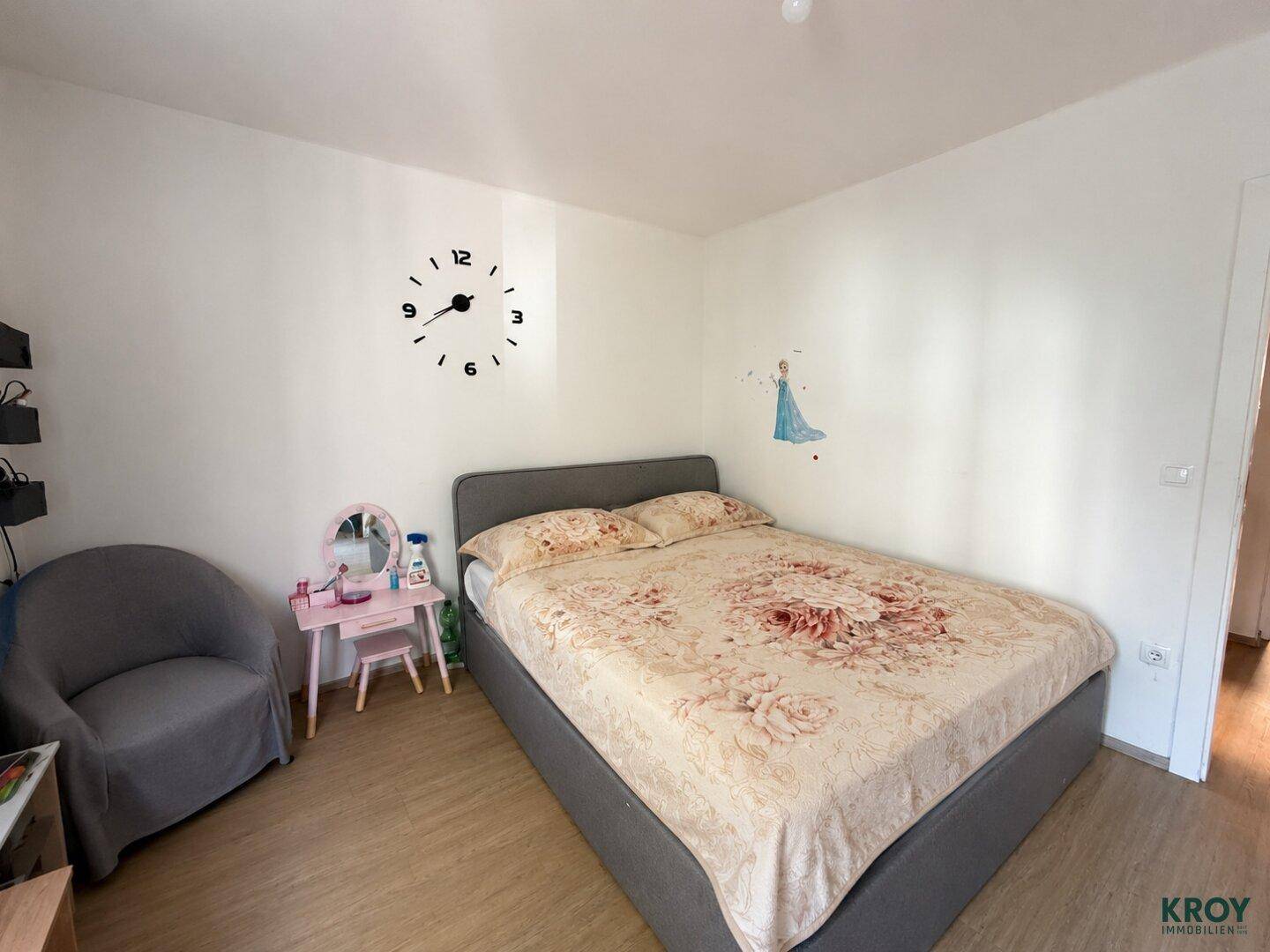 Schlafzimmer mit Doppelbett, floraler Bettwäsche und kleiner Schminkkonsole.