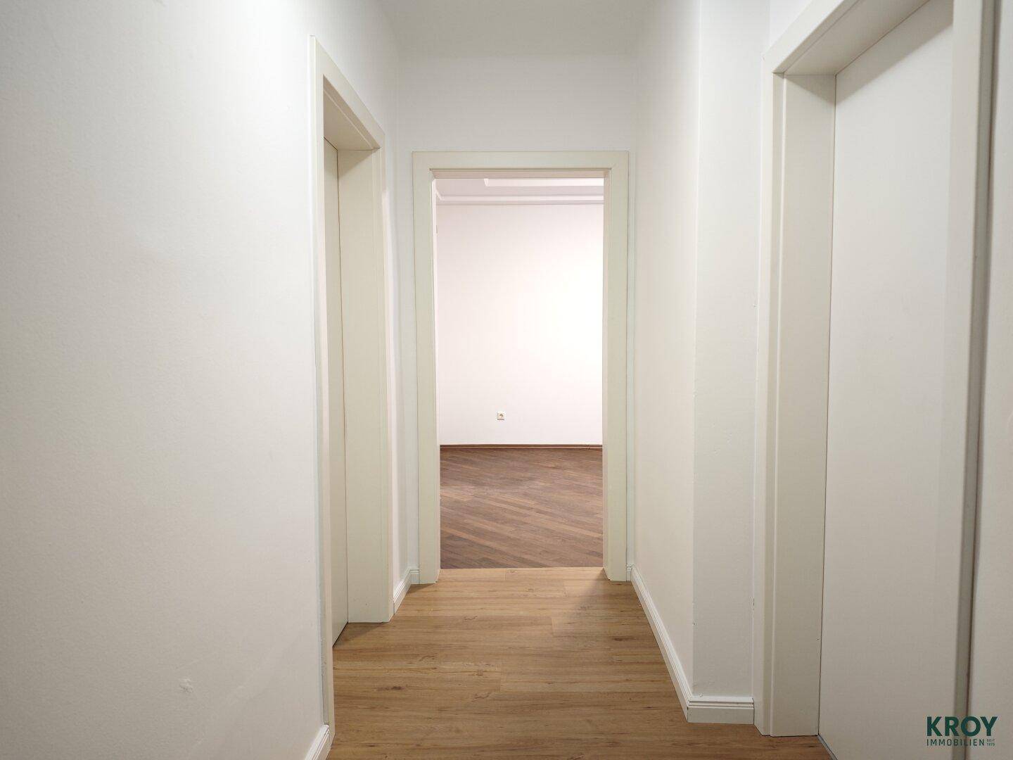 Heller Flur mit hellem Holzboden, der zu den verschiedenen Räumen der Wohnung führt.