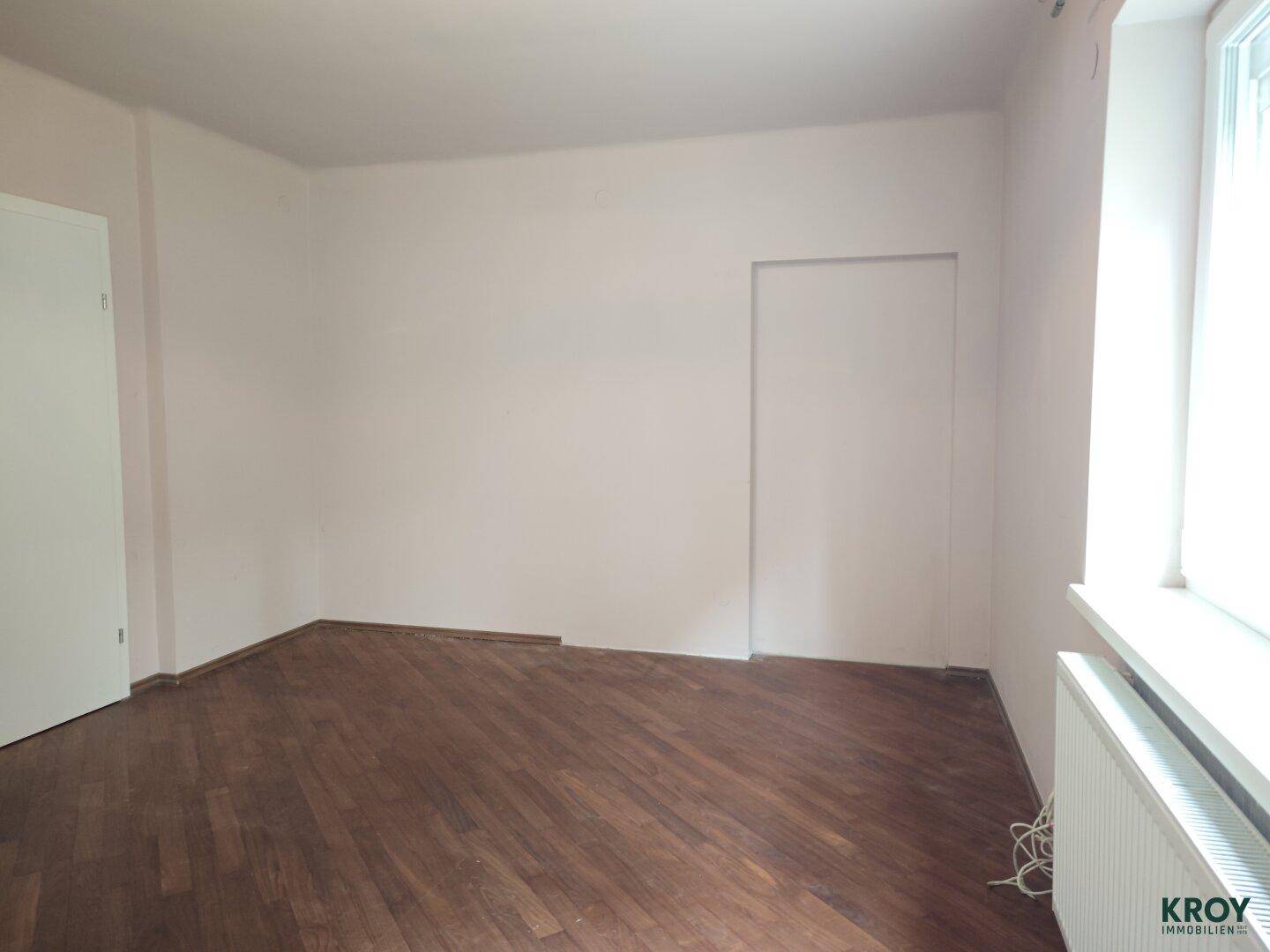 Helles Zimmer mit Holzboden und einem Fenster, das für natürliche Belichtung sorgt.
