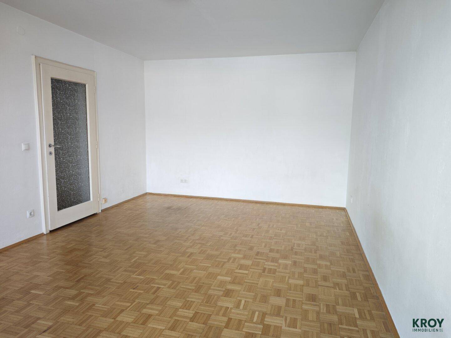 Heller Raum mit Parkettboden und einer Tür mit Glaseinsatz, bereit zur individuellen Gestaltung.