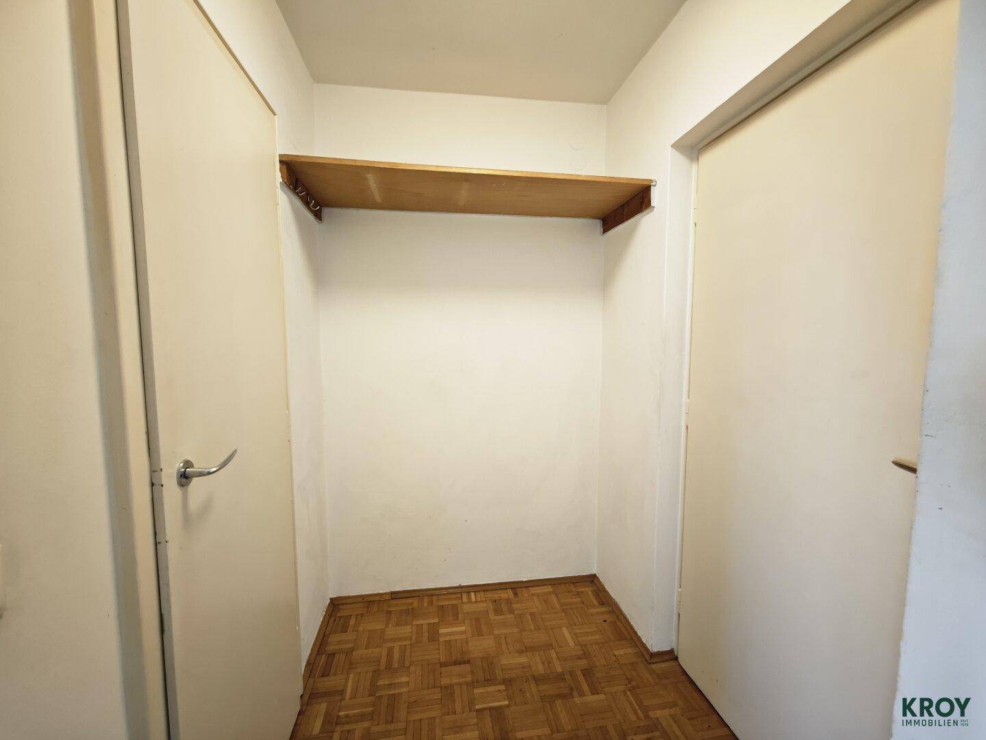 Kleiner Abstellraum mit Holzregal und Parkettboden, ideal für zusätzlichen Stauraum.