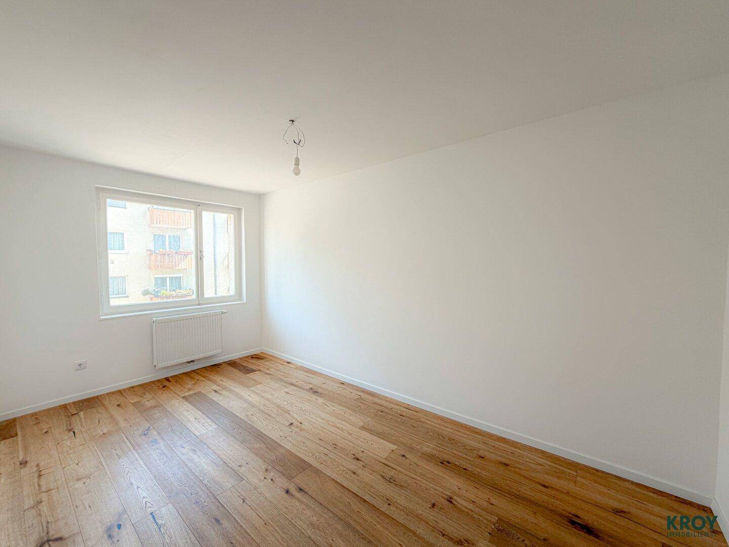 Helles Zimmer mit Holzboden und Fenster, ideal als Schlafzimmer oder Kinderzimmer.