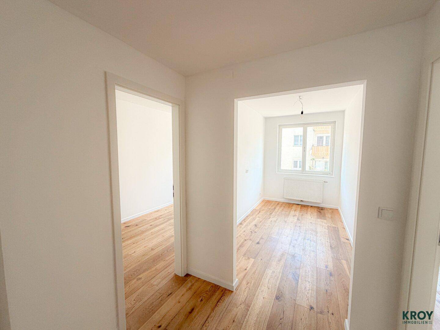 Heller Übergangsbereich mit Holzboden, der zu zwei weiteren Zimmern führt.