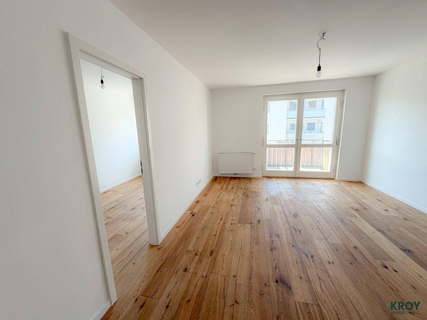 Großzügiges Zimmer mit Holzboden und weiß gestrichenen Wänden, bereit für die Einrichtung.