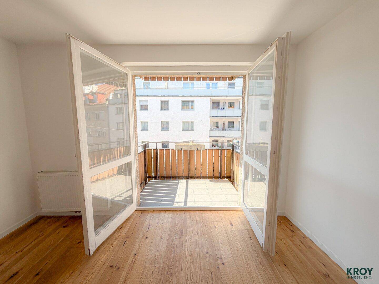 Lichtdurchflutetes Zimmer mit geöffneten Balkontüren und Blick auf den Außenbereich.
