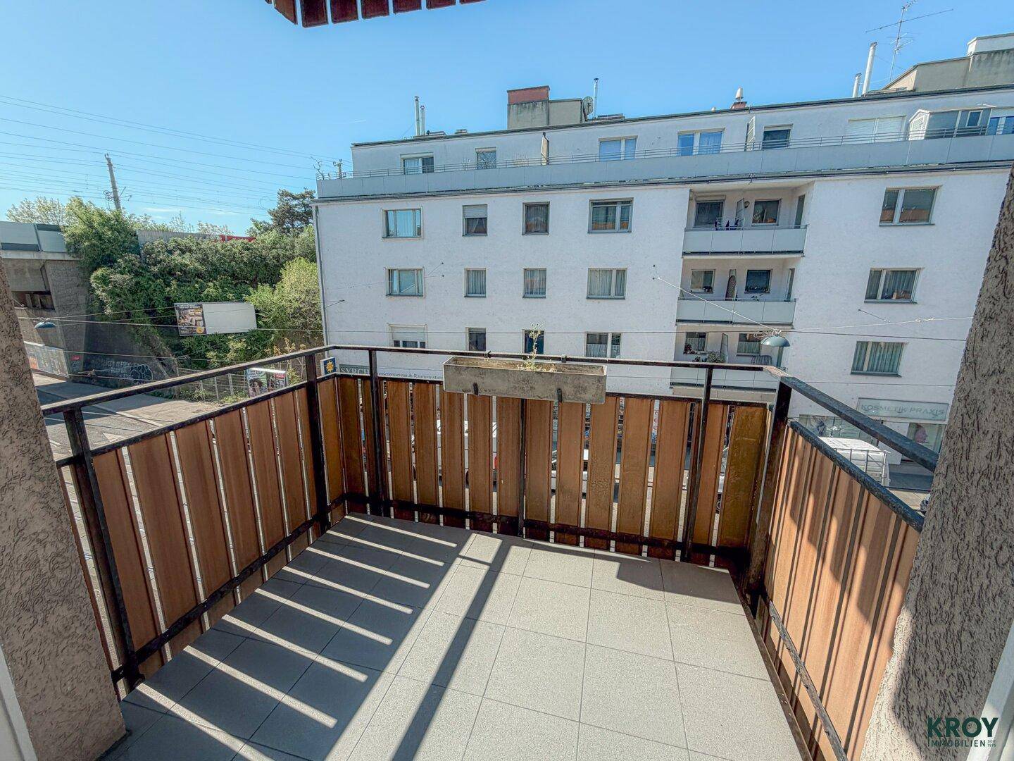 Geräumiger Balkon mit Fliesenboden und Holzverkleidung, bietet Platz für Entspannung im Freien.