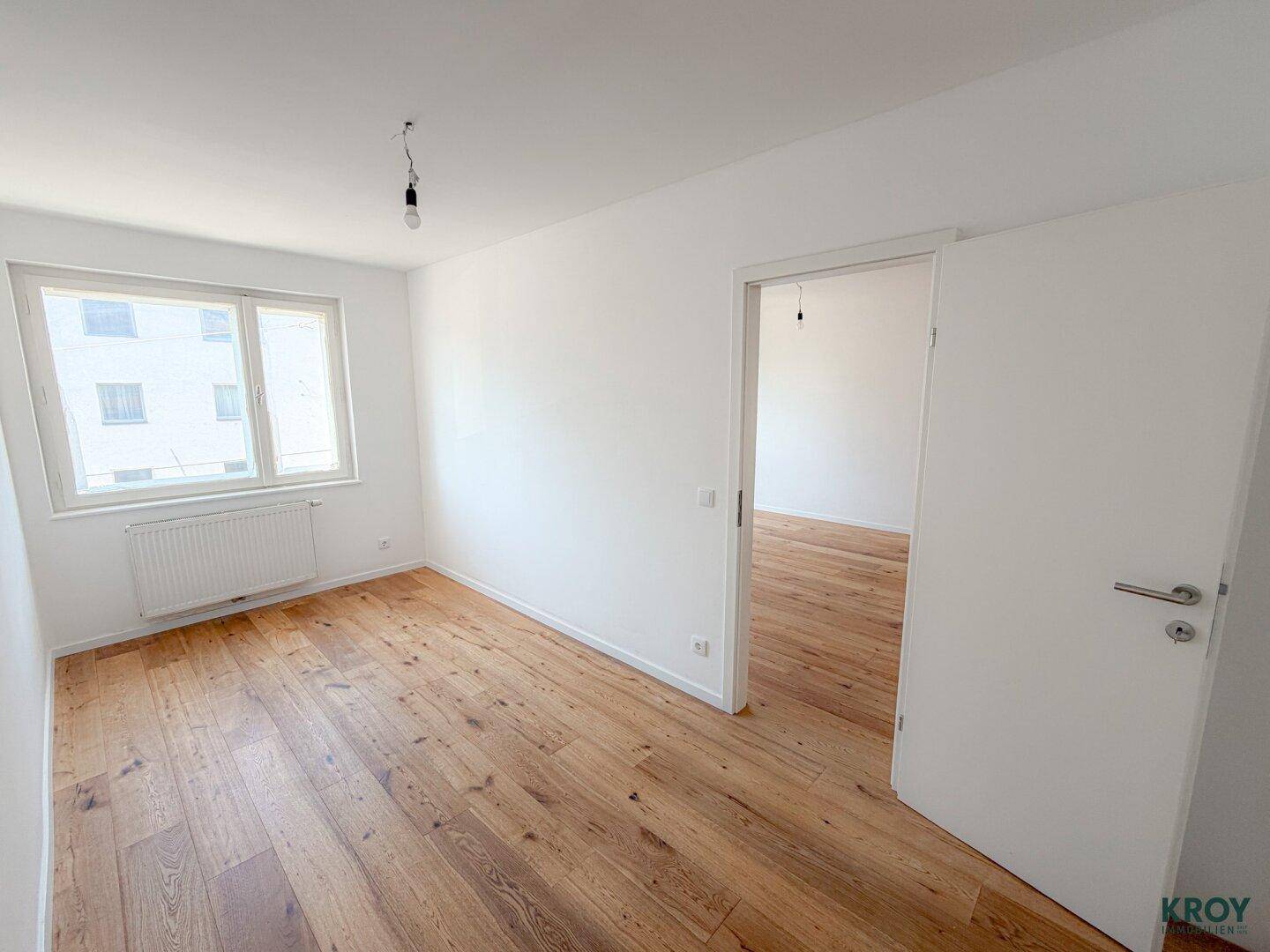Helles Schlafzimmer mit Holzboden und großem Fenster, bietet viel Tageslicht.