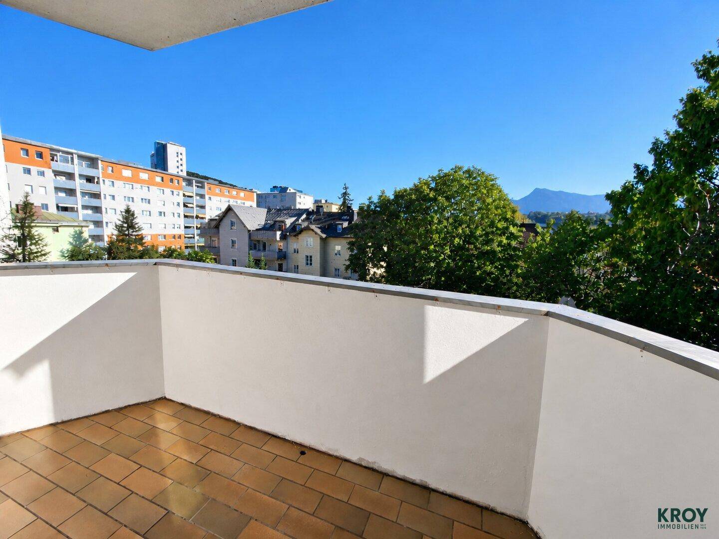 Geräumiger Balkon mit Fliesenboden und weitem Blick über die Stadt und die Berge.