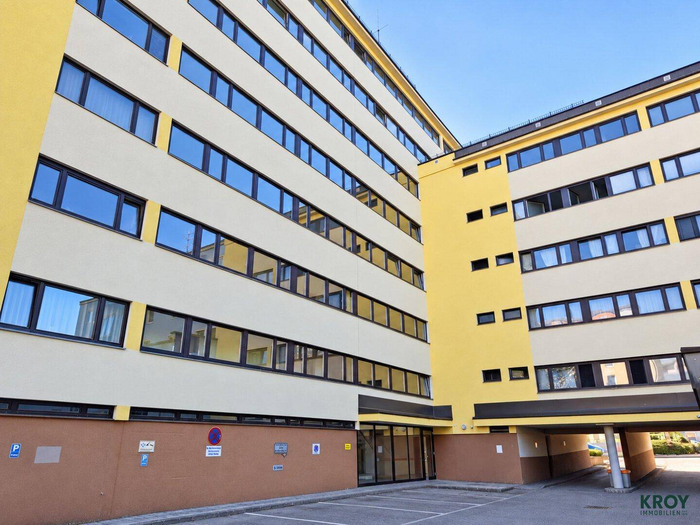 Großes Wohngebäude mit moderner Architektur, vielen Fenstern und hellgelber Fassade.