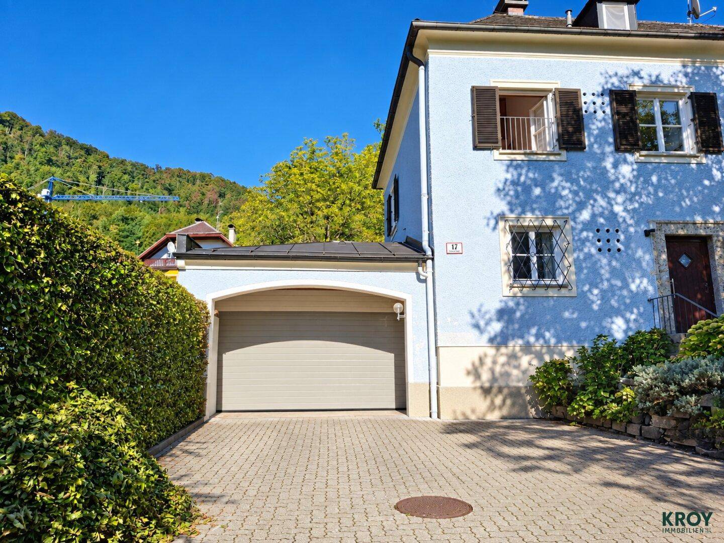 Einfahrt zum Haus mit Doppelgarage und gepflastertem Vorplatz.