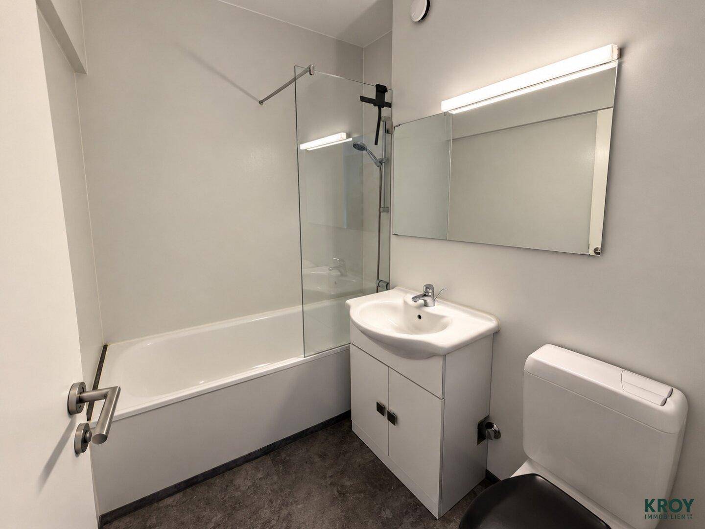 Modernes Badezimmer mit Badewanne, Duschabtrennung und Waschtischunterschrank.