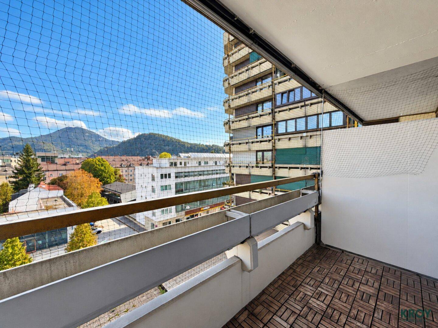 Balkon mit Holzboden und Schutznetz, bietet einen weiten Blick auf die Stadt und die Berge.