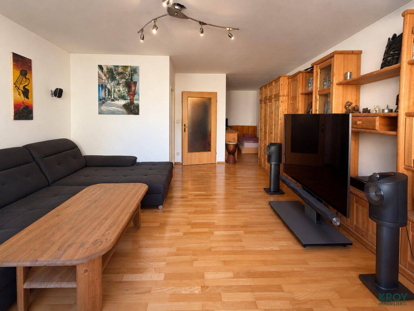 Heller Wohnbereich mit Holzboden, Holzmöbeln und Blick auf den angrenzenden Flur.