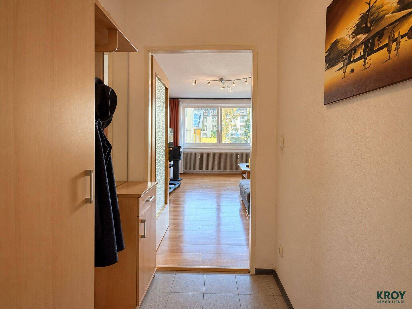 Heller Flur mit Garderobe, Fliesenboden und Blick in das angrenzende Wohnzimmer.