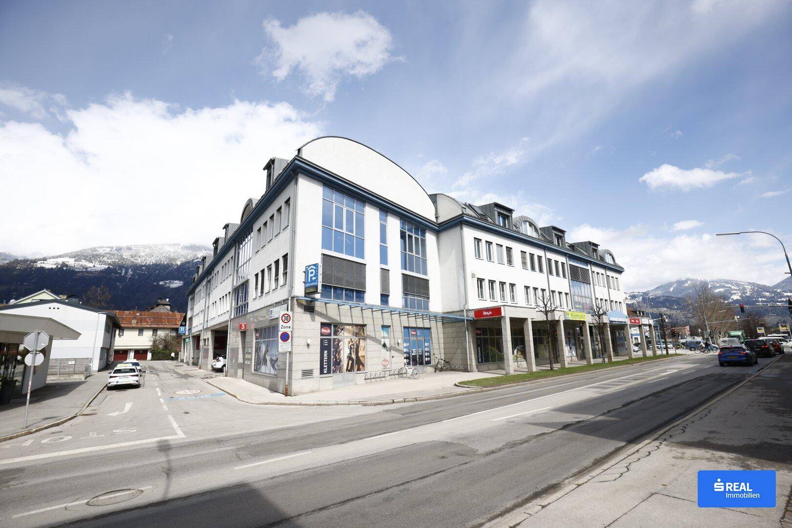 Modernes Geschäftsgebäude mit markanter Architektur, großen Fenstern und Blick auf die umliegenden Berge.