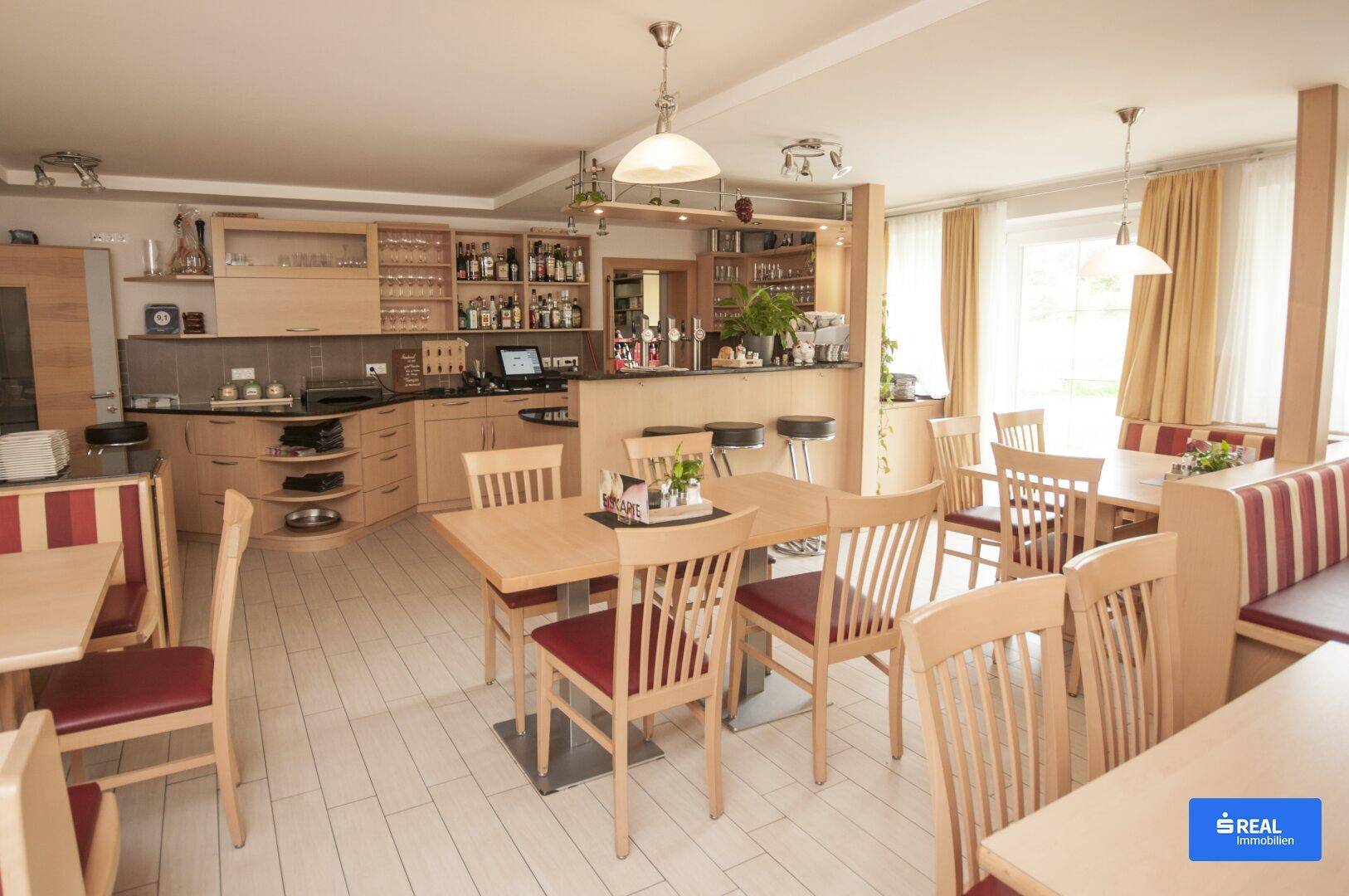 Geräumiger Restaurant-Essbereich mit Holztischen, gepolsterten Bänken und einer voll ausgestatteten Bar.