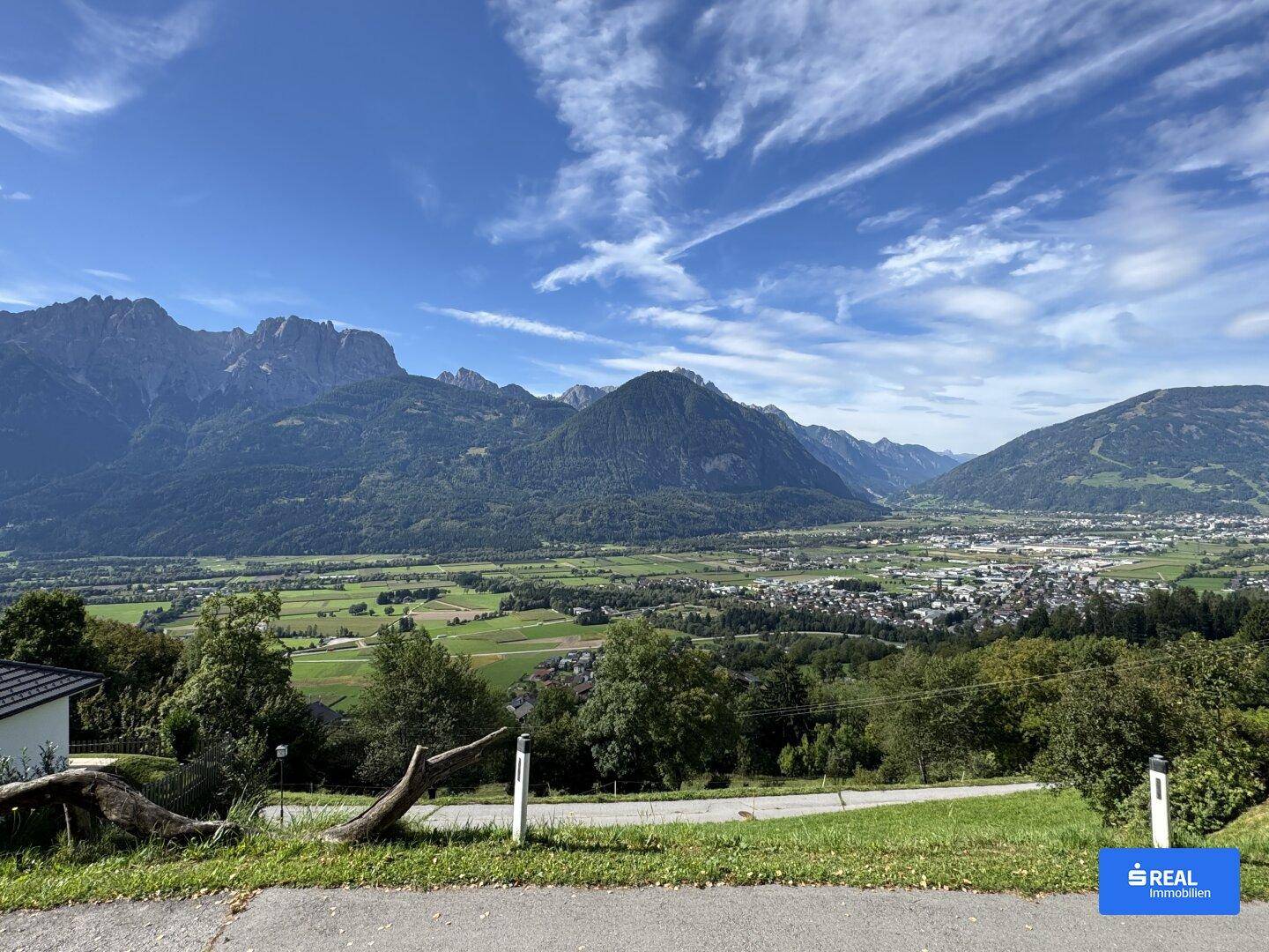 Panoramablick auf die umliegende Berglandschaft und das weite Tal unter blauem Himmel.