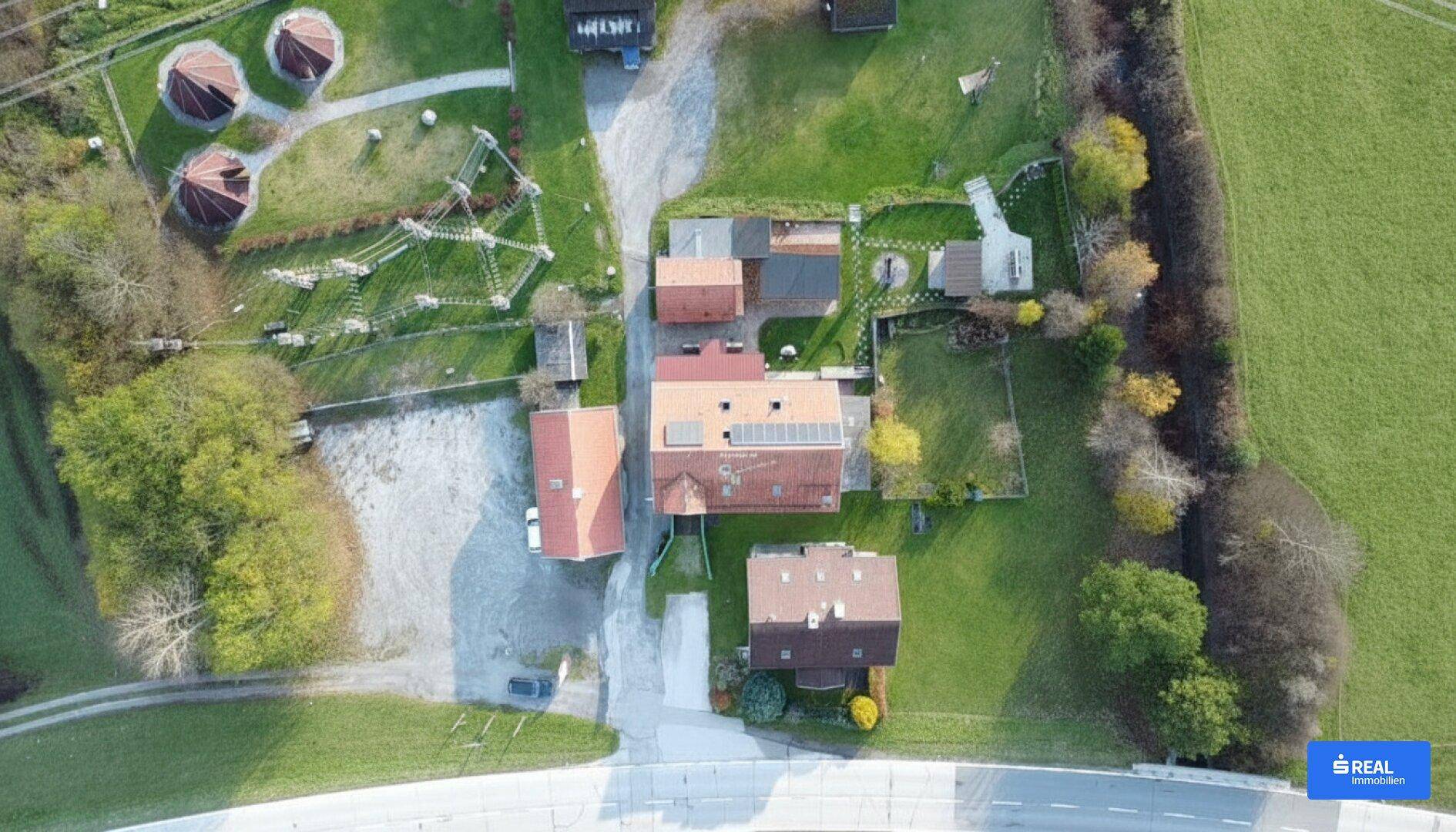 Luftaufnahme des Anwesens mit mehreren Gebäuden, Grünflächen und Freizeiteinrichtungen in ländlicher Umgebung.