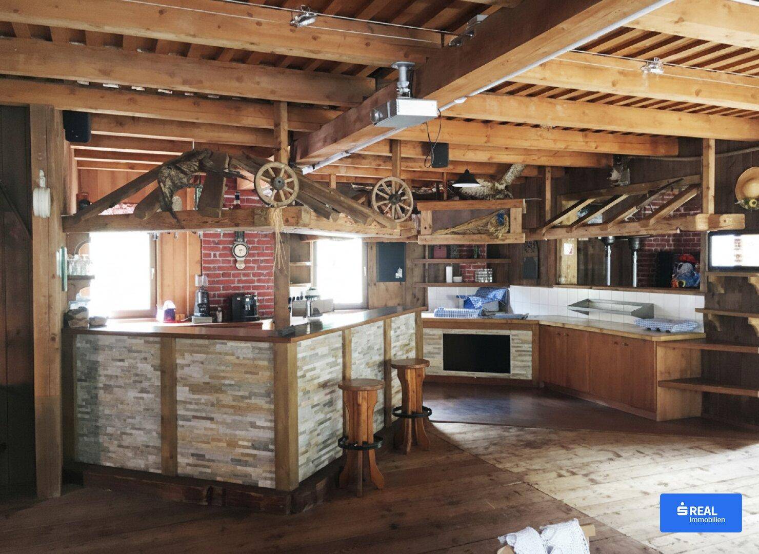 Rustikaler Innenraum mit viel Holz, sichtbaren Balken und einer Bar mit Steinverkleidung.