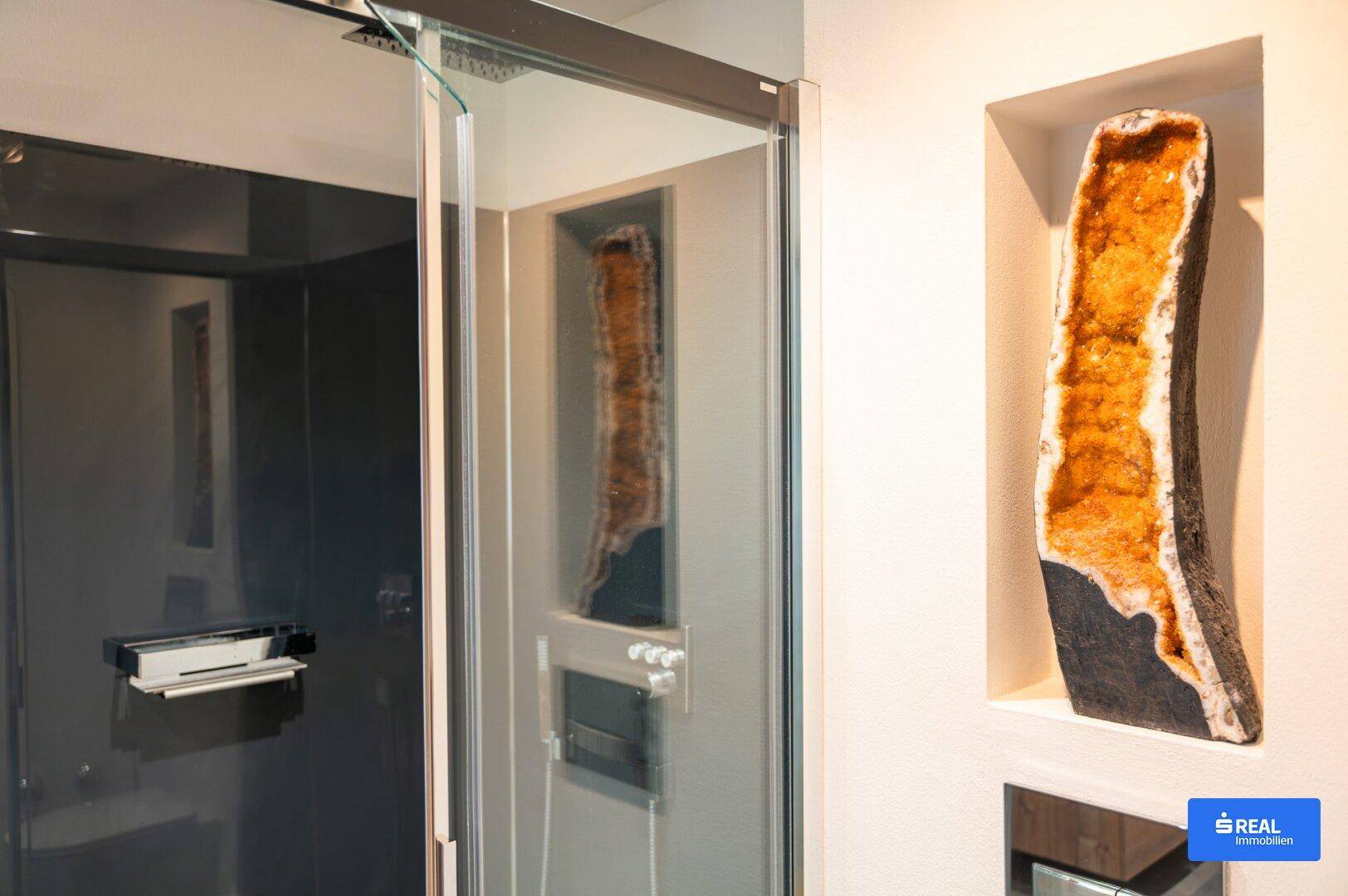 Detailansicht der modernen begehbaren Dusche mit dunklem Interieur und dekorativer Kristallnische.