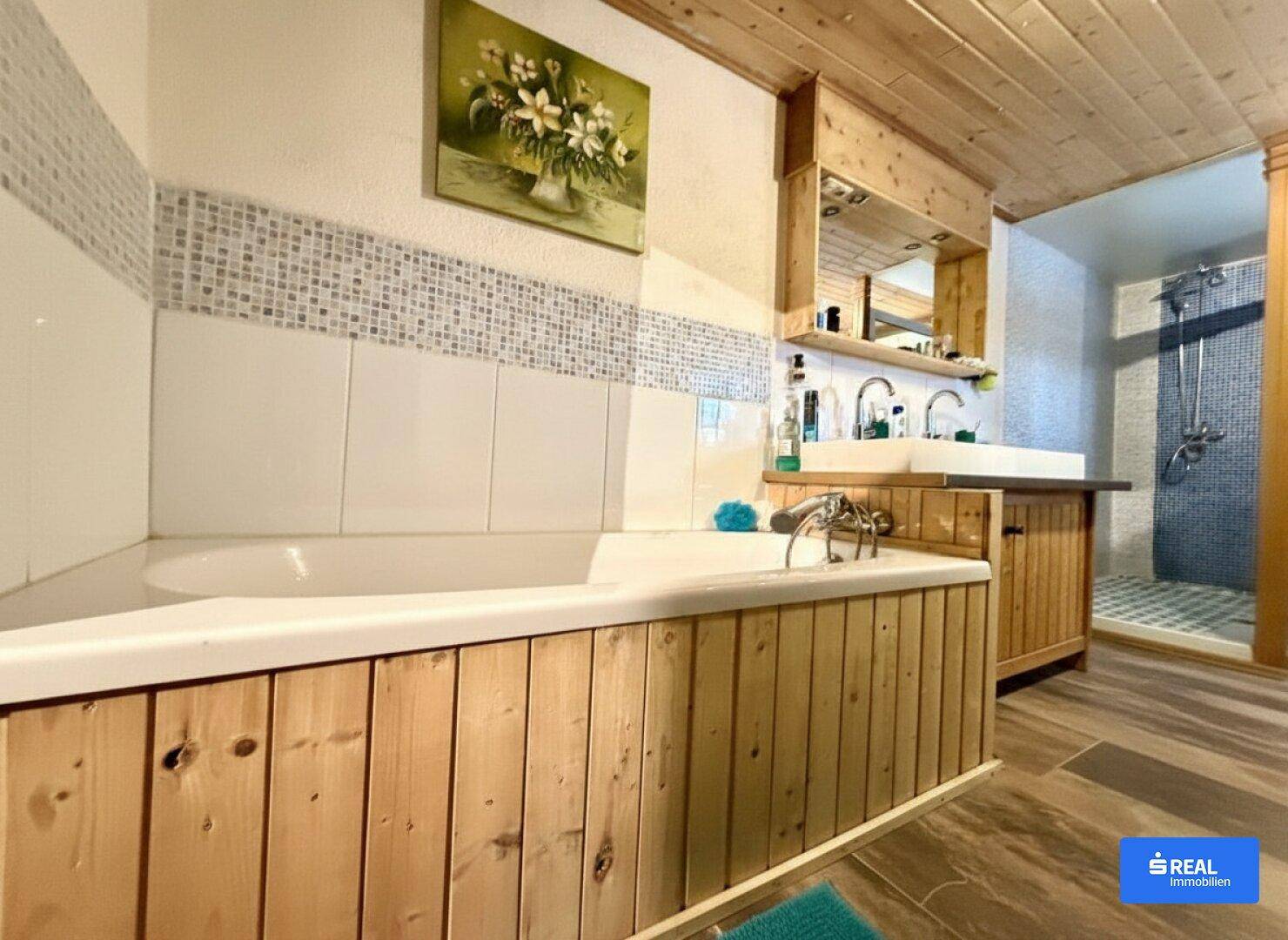 Badezimmer mit Holzverkleidung, Badewanne und separater Duschkabine.