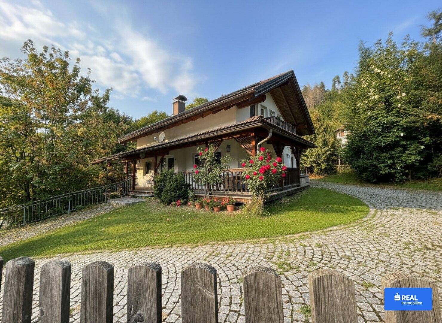 Charmantes Einfamilienhaus mit gepflegtem Garten, Rosensträuchern und geschwungener Auffahrt.