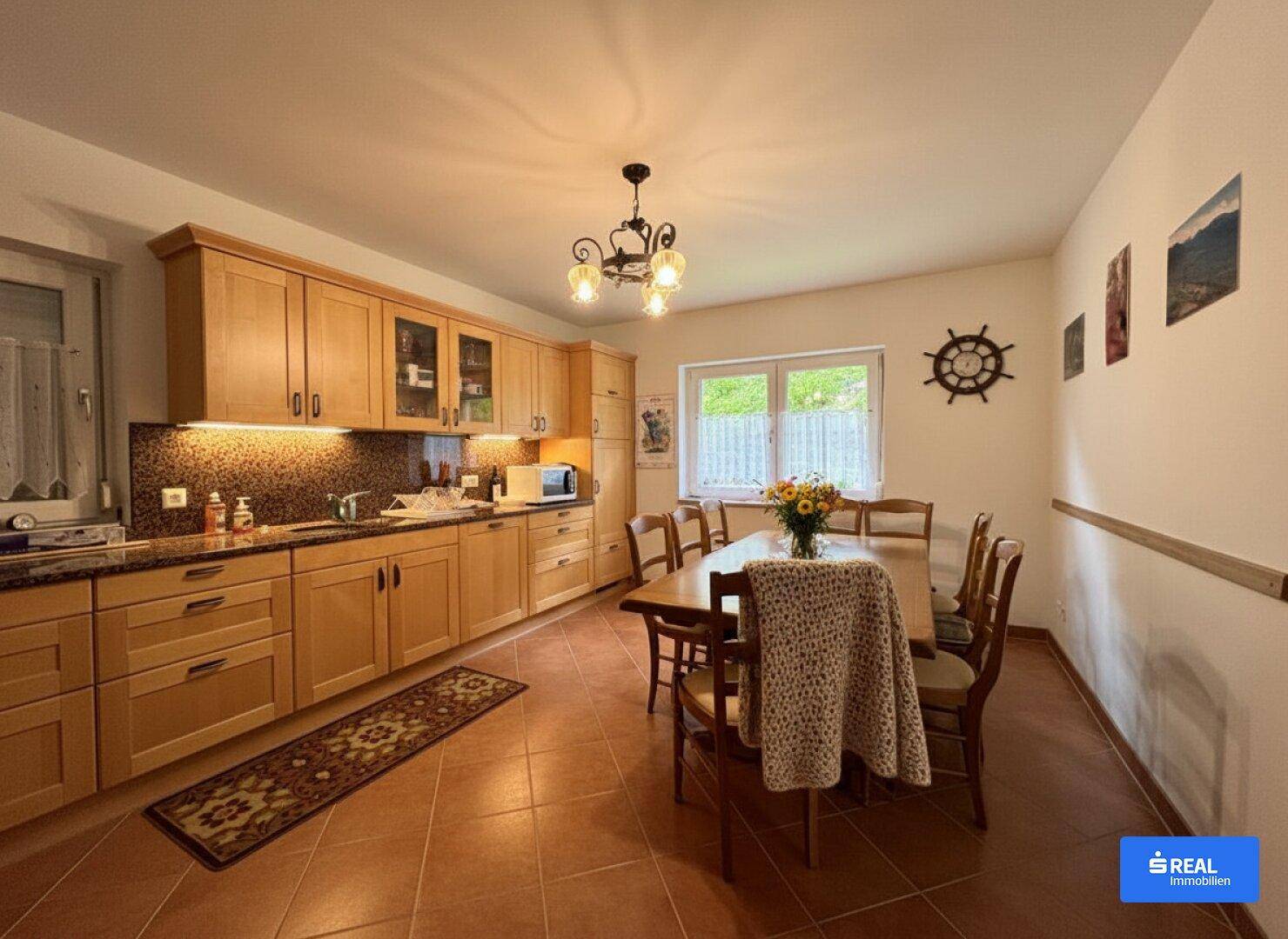 Geräumige Wohnküche mit Holzschränken, Terrakottaboden und einem Esstisch für die Familie.
