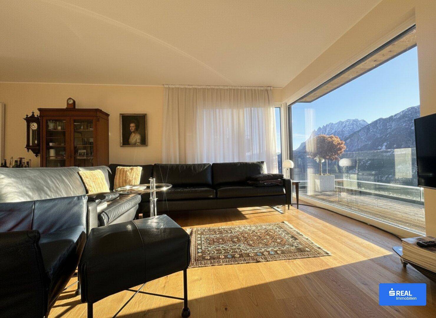 Helles Wohnzimmer mit bequemen Sofas, Holzboden und weitem Bergblick durch die großen Fenster.