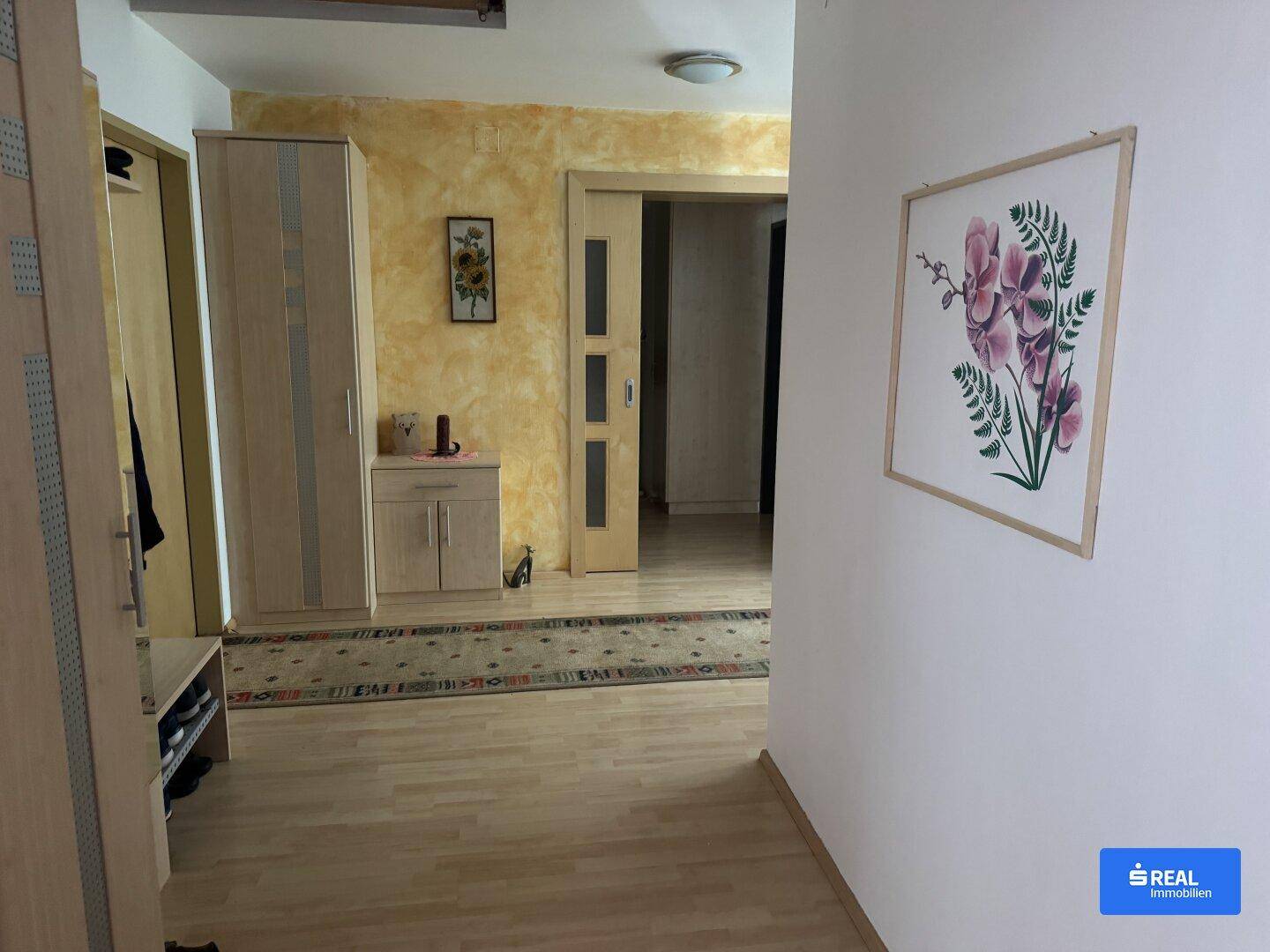 Geräumiger Flur mit Laminatboden, Garderobenschrank und dekorativer Wandgestaltung.
