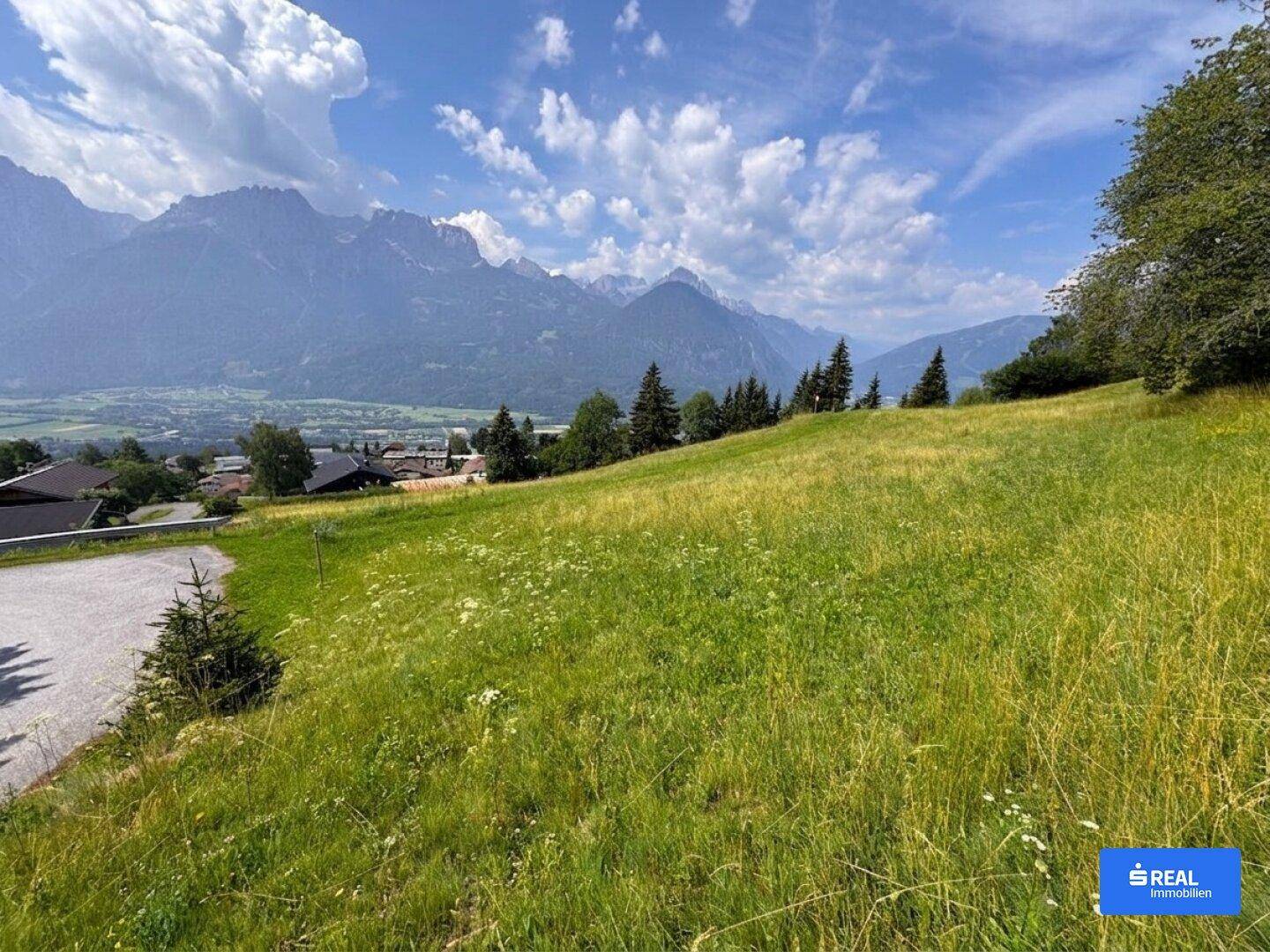 Idyllische Hügellandschaft mit weitem Blick auf die majestätischen Berge und das Tal.